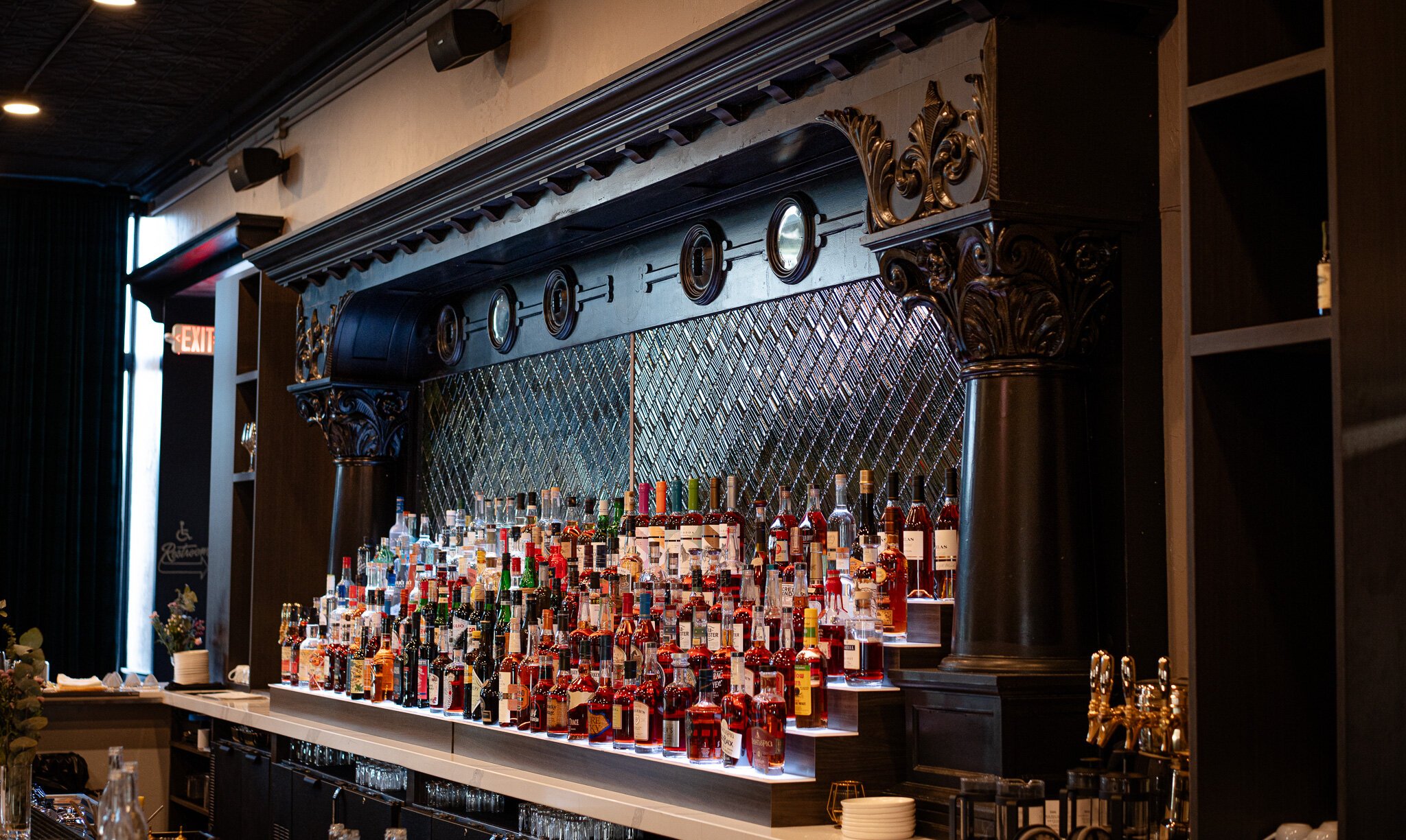 The refurbished back bar features woodworking details and green tiles.