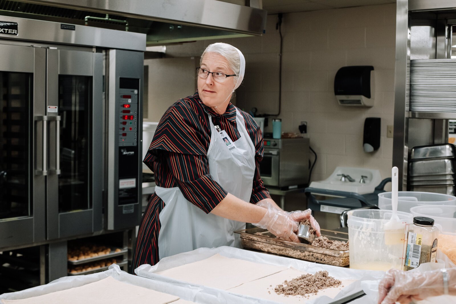 Landes's staff member Judith Brovont, left, prepares sausage bread for lunch at Manchester Junior-Senior High School, which features local pork from 4-H.