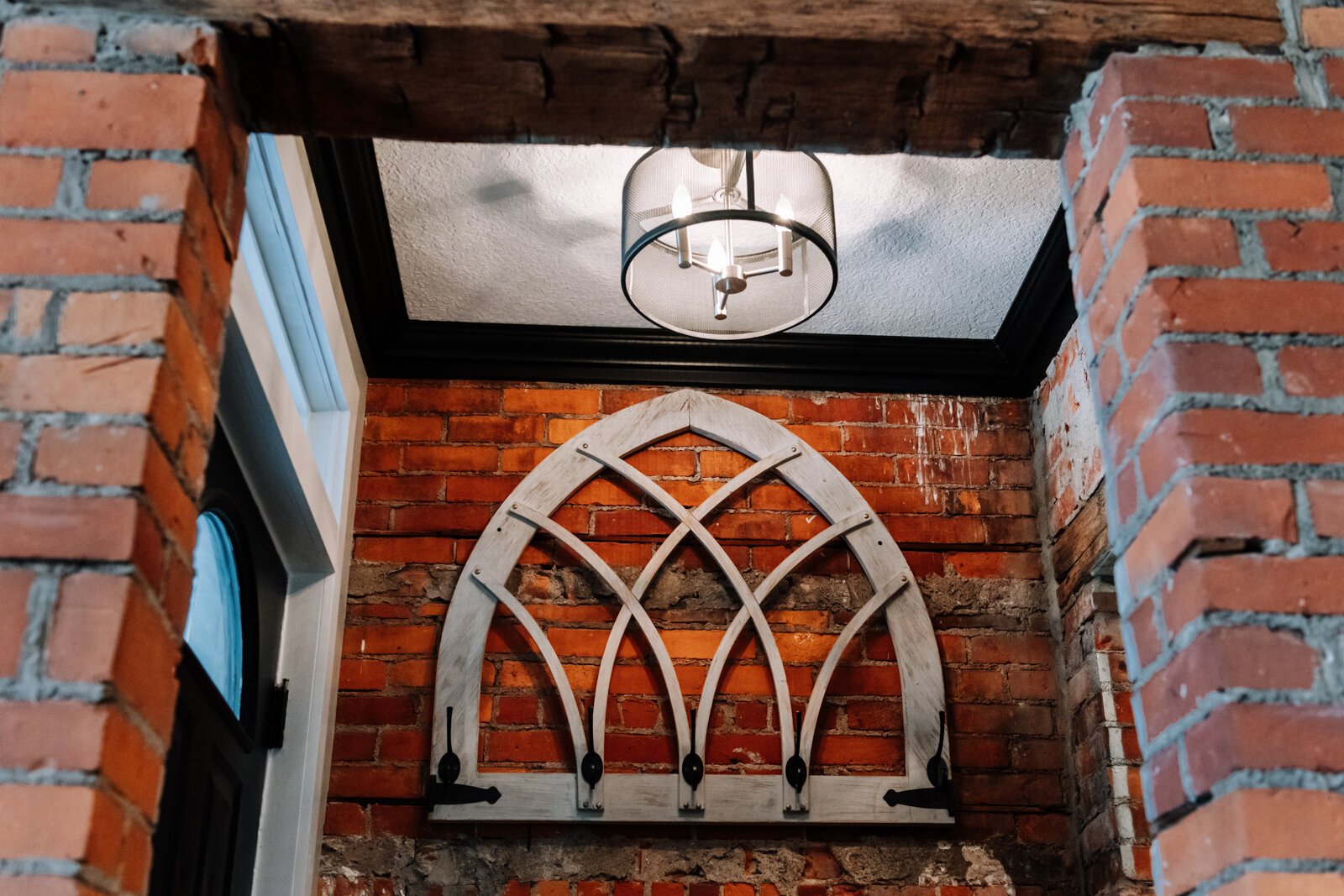 The entryway features exposed brick and coat hooks on the bottom floor.