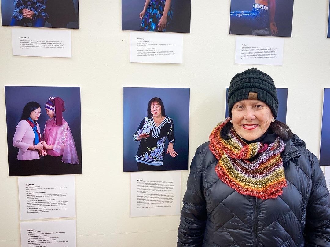 Ana Giusti stands next to a picture of herself displayed on the wall at Creative Women of the World’s shop in downtown Fort Wayne.