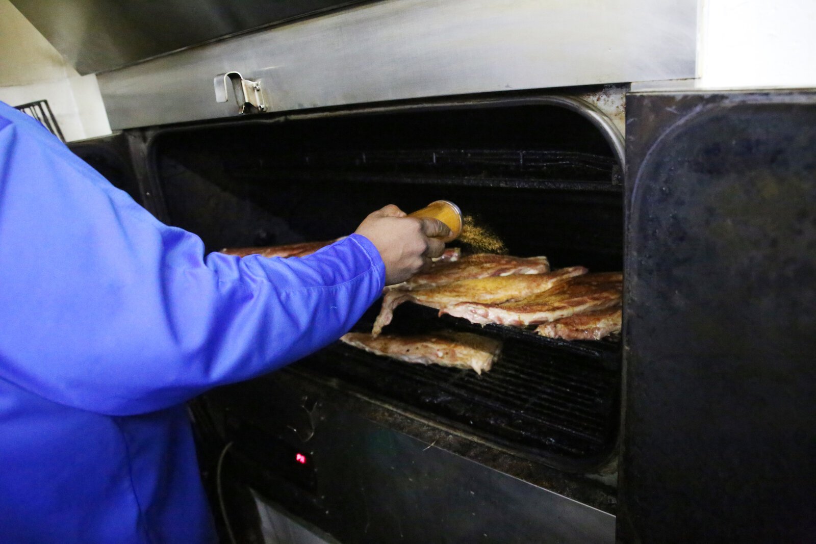 Curry seasons meat in his famous Ooh Wee BBQ seasoning.