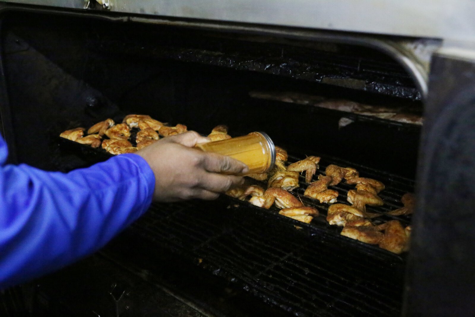 Curry seasons meat in his famous Ooh Wee BBQ seasoning.