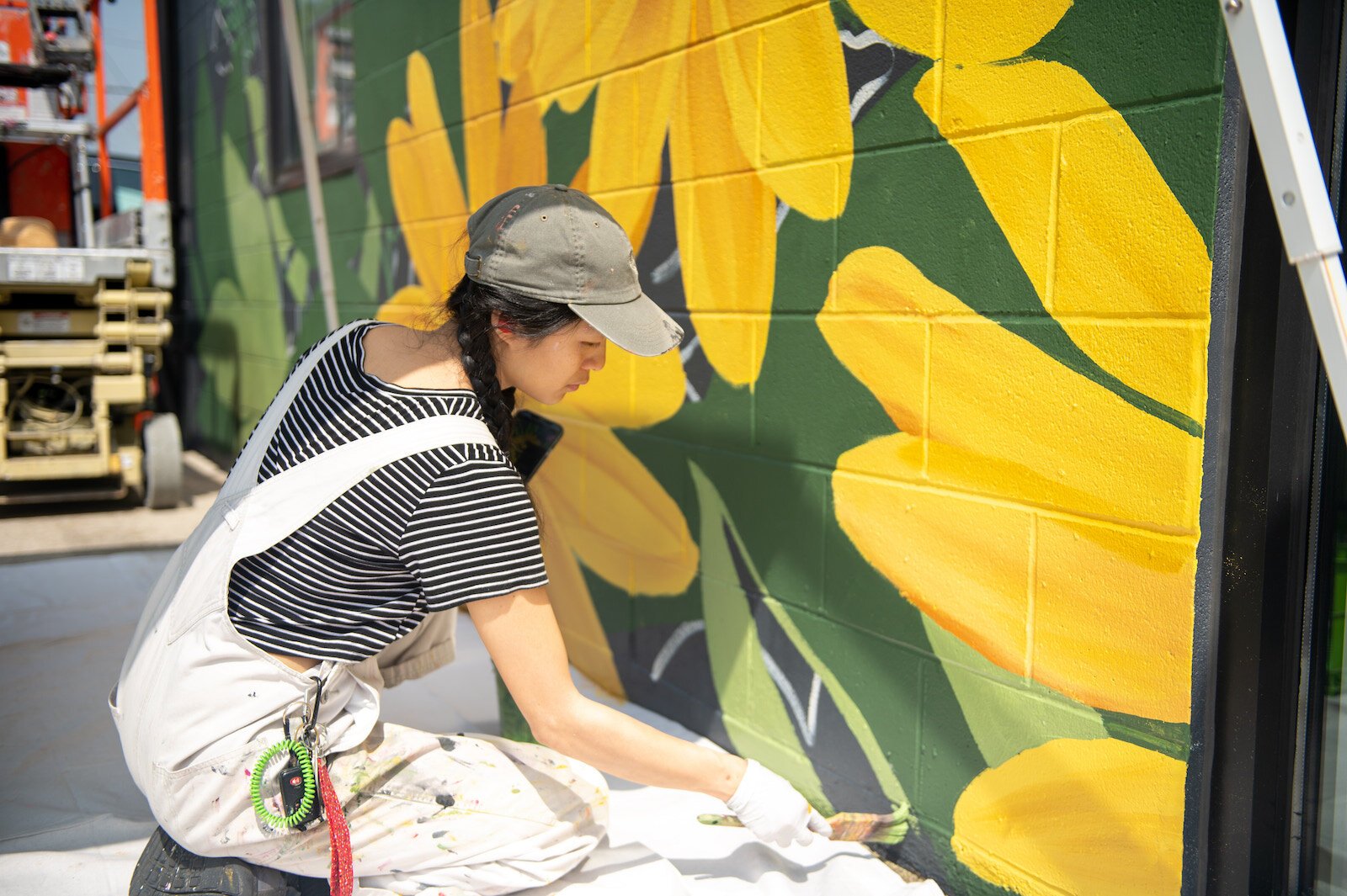 Detroit-based artist Louise 'Ouizi' Jones paints a mural in downtown Roanoke inspired by common Indiana flowers, including peonies and black-eyed Susans.