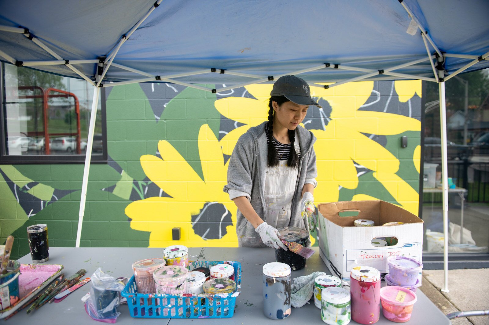 Detroit-based artist Louise 'Ouizi' Jones paints a mural in downtown Roanoke inspired by common Indiana flowers, including peonies and black-eyed Susans.