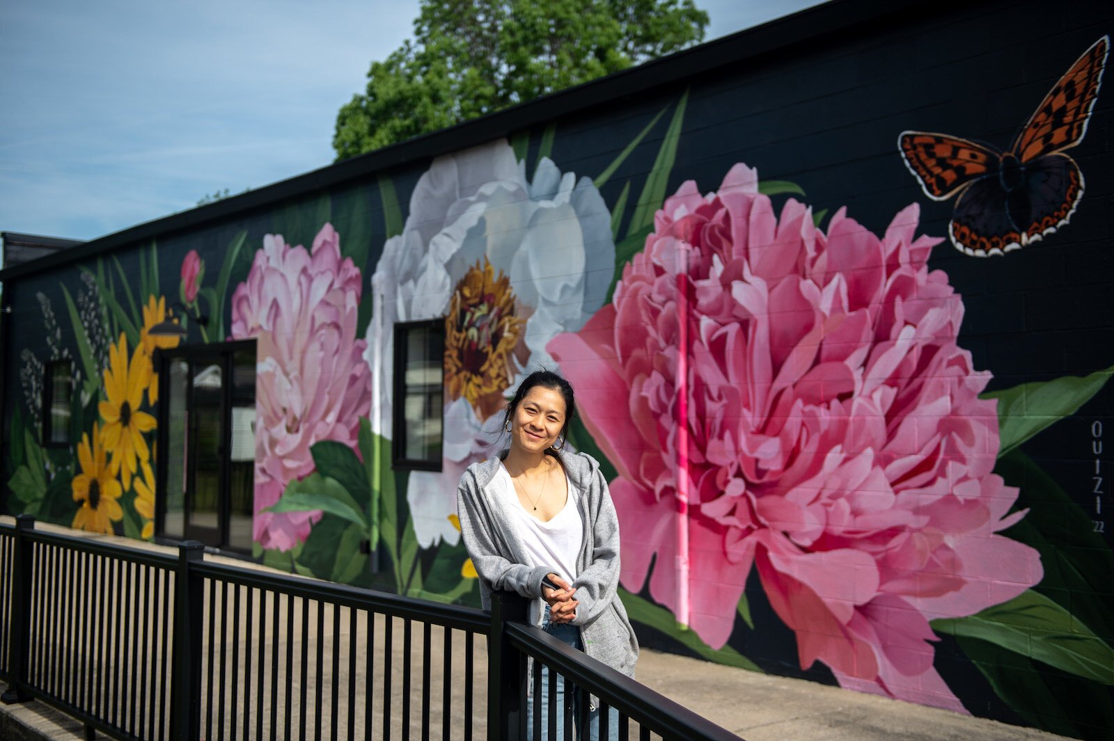 Detroit-based artist Louise 'Ouizi' Jones paints a mural in downtown Roanoke inspired by common Indiana flowers, including peonies and black-eyed Susans.
