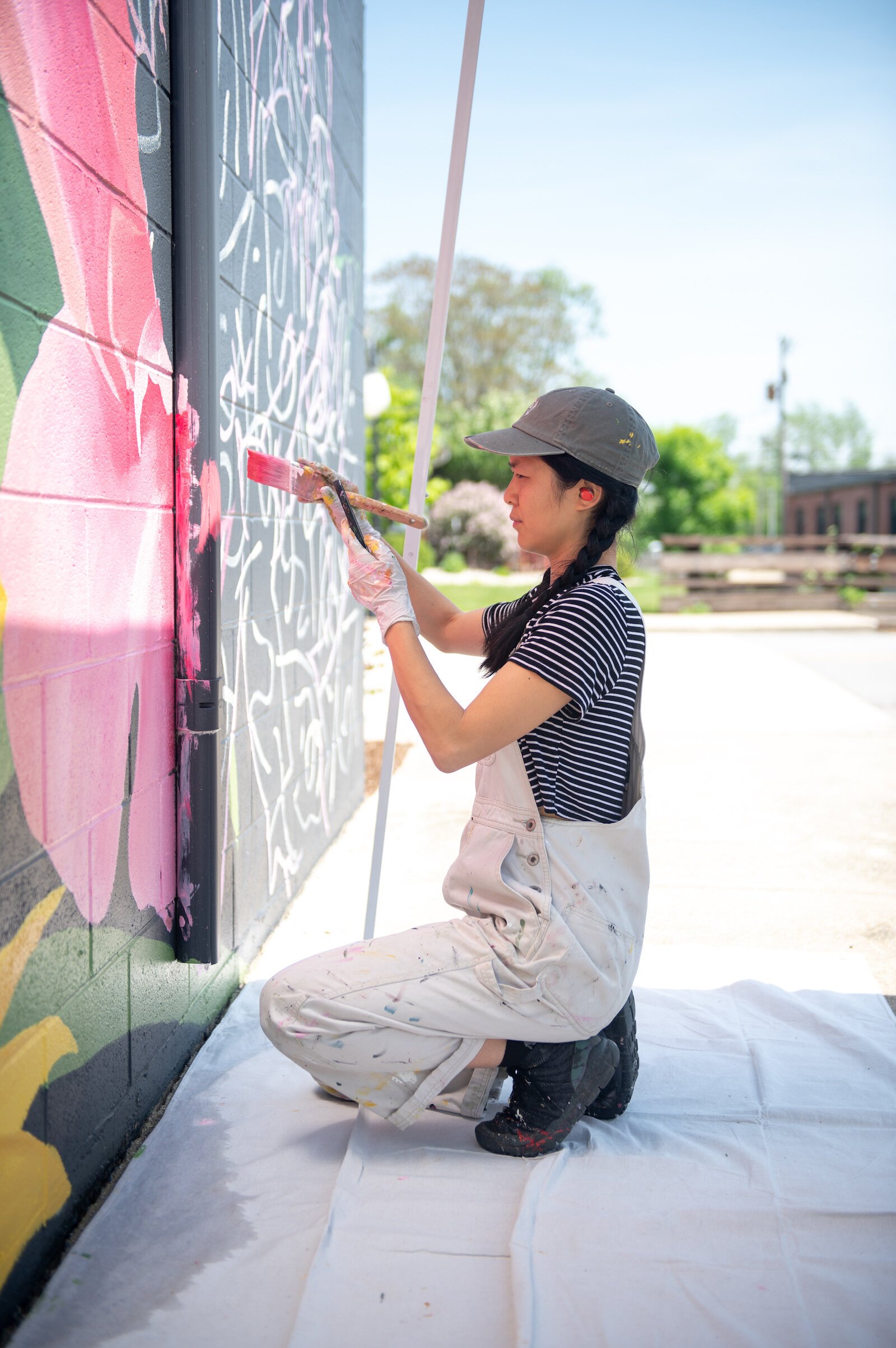 Detroit-based artist Louise 'Ouizi' Jones paints a mural in downtown Roanoke inspired by common Indiana flowers, including peonies and black-eyed Susans.