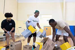From right: Bigger Than Us volunteers Carmen Lowe and Lorenzo Holder help CEO of BTU Jerrell Holman with cleaning up boxes before the start of the Book Bag Giveaway at Renaissance Pointe YMCA, 2323 Bowser Ave. on August 7, 2021.