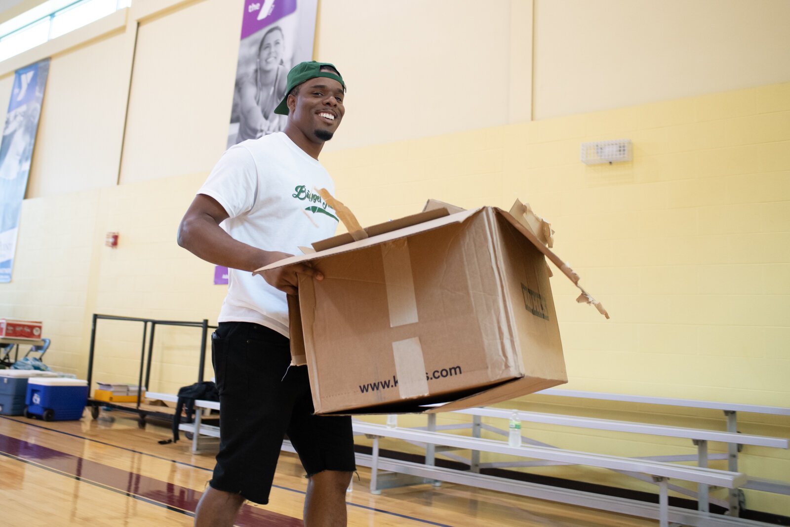 Bigger Than Us volunteer Lorenzo Holman is all smiles as he helps by cleaning up boxes before the start of the Book Bag Giveaway at Renaissance Pointe YMCA, 2323 Bowser Ave.