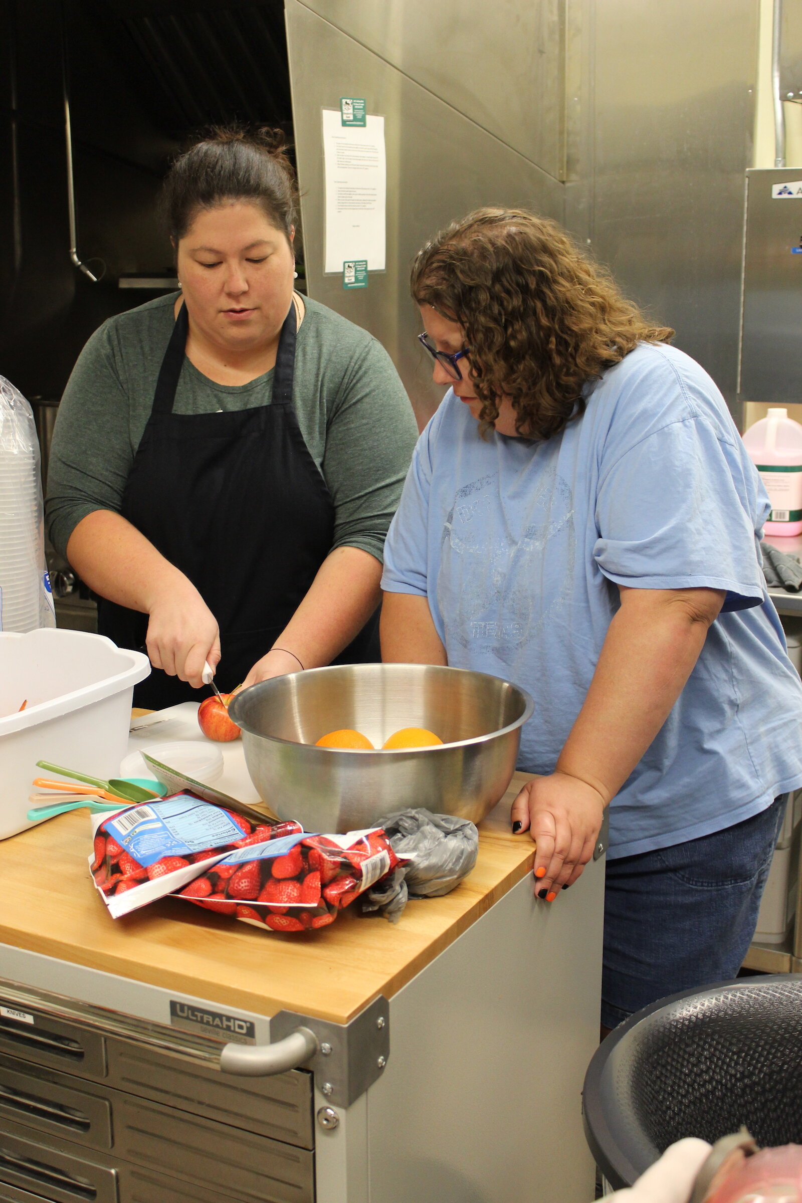 Kim Trombley works with class participant Kalisha Doty as they cut apples ahead of the Our HEALing Kitchen class at Shepherd’s Hand.