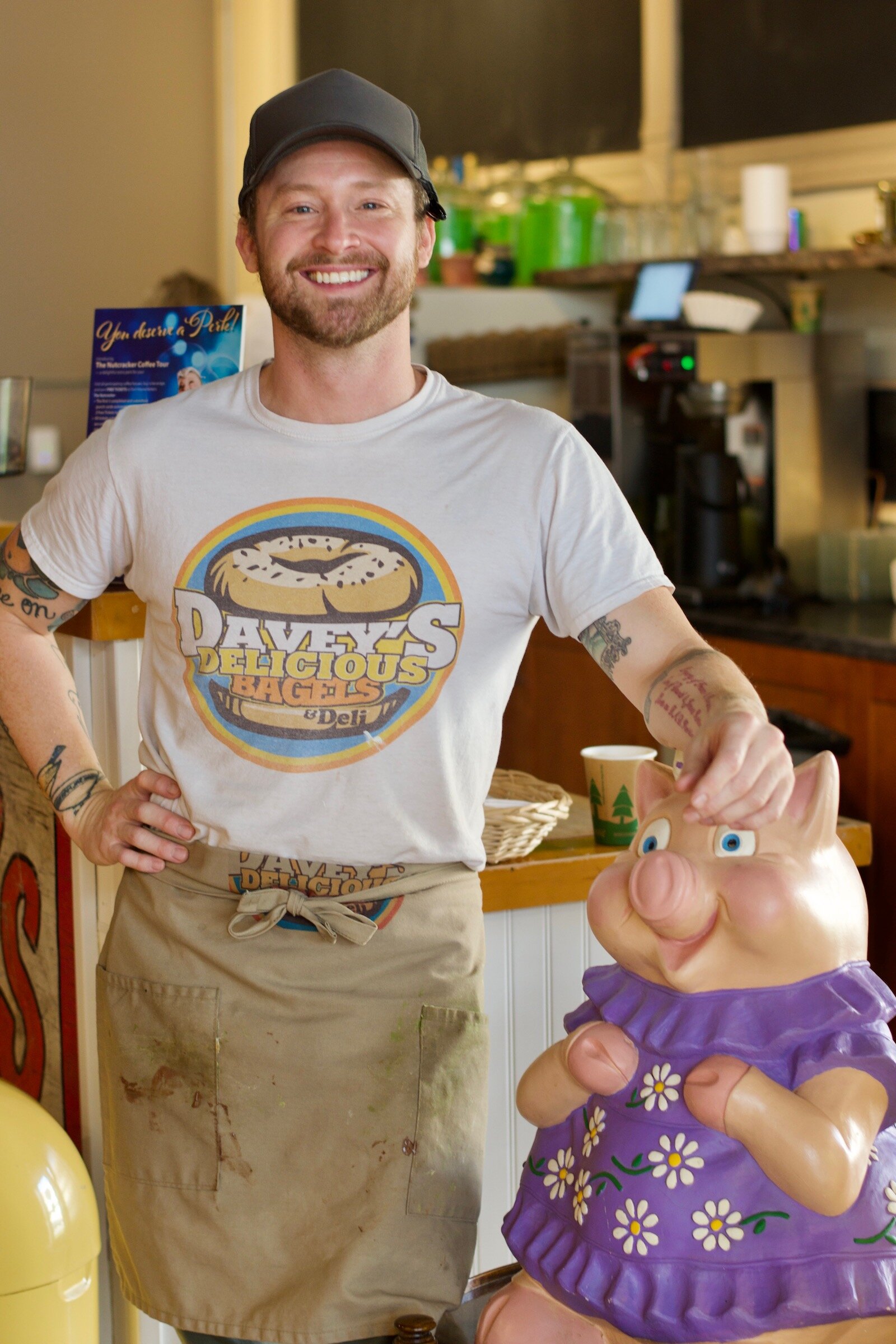 Davey Heritier poses with "Peggy the Piggy" at Davey's Delicious Bagels who is collecting donations for Charis House until Dec. 22, 2021.