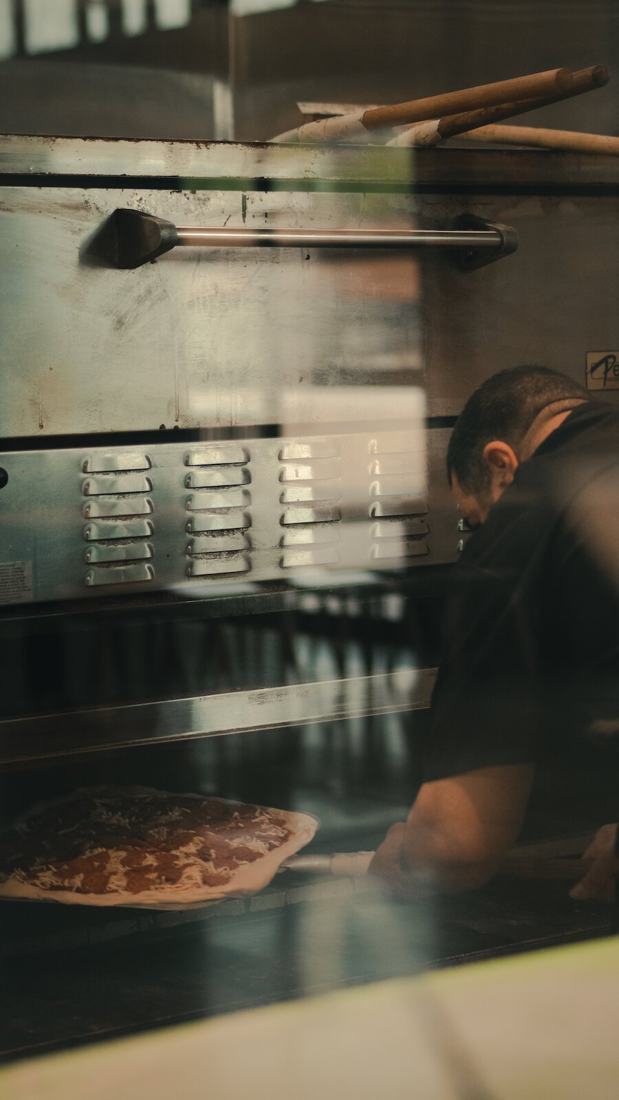 Johnny Bojinoff, owner of Johnny OX Pizzeria, puts a pizza in the oven.