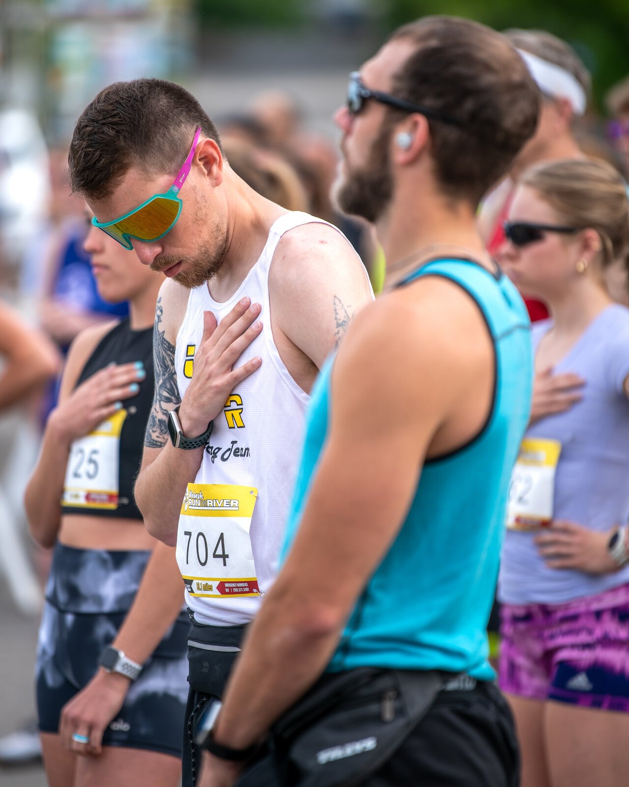 Runners at the start line listen to the National Anthem. 