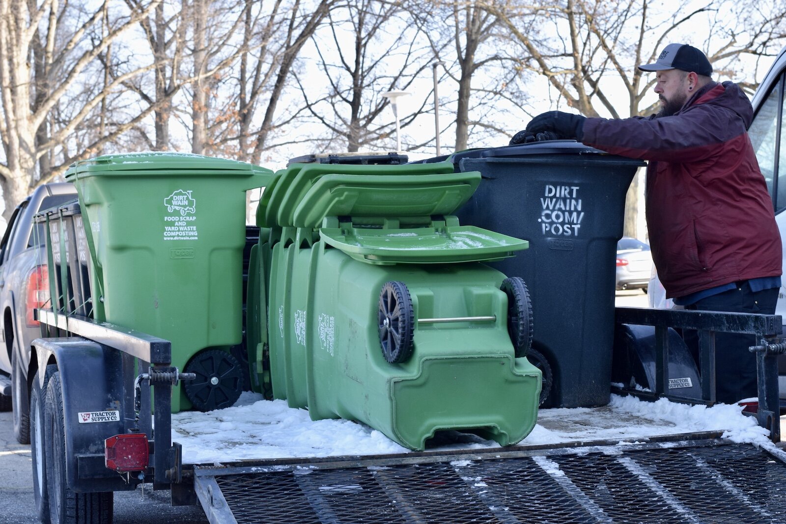 Dirt Wain’s Founder Brett Bloom loads compost bins into a pickup truck.