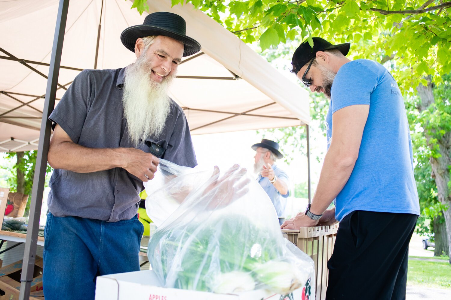 Myron Metzger with Berry Hill Farm helps customer Aaron Butts, Chef at Copper Spoon, with his weekly order during the Fort Wayne's Farmers Market at McCulloch Park on Saturday June 19, 2021.