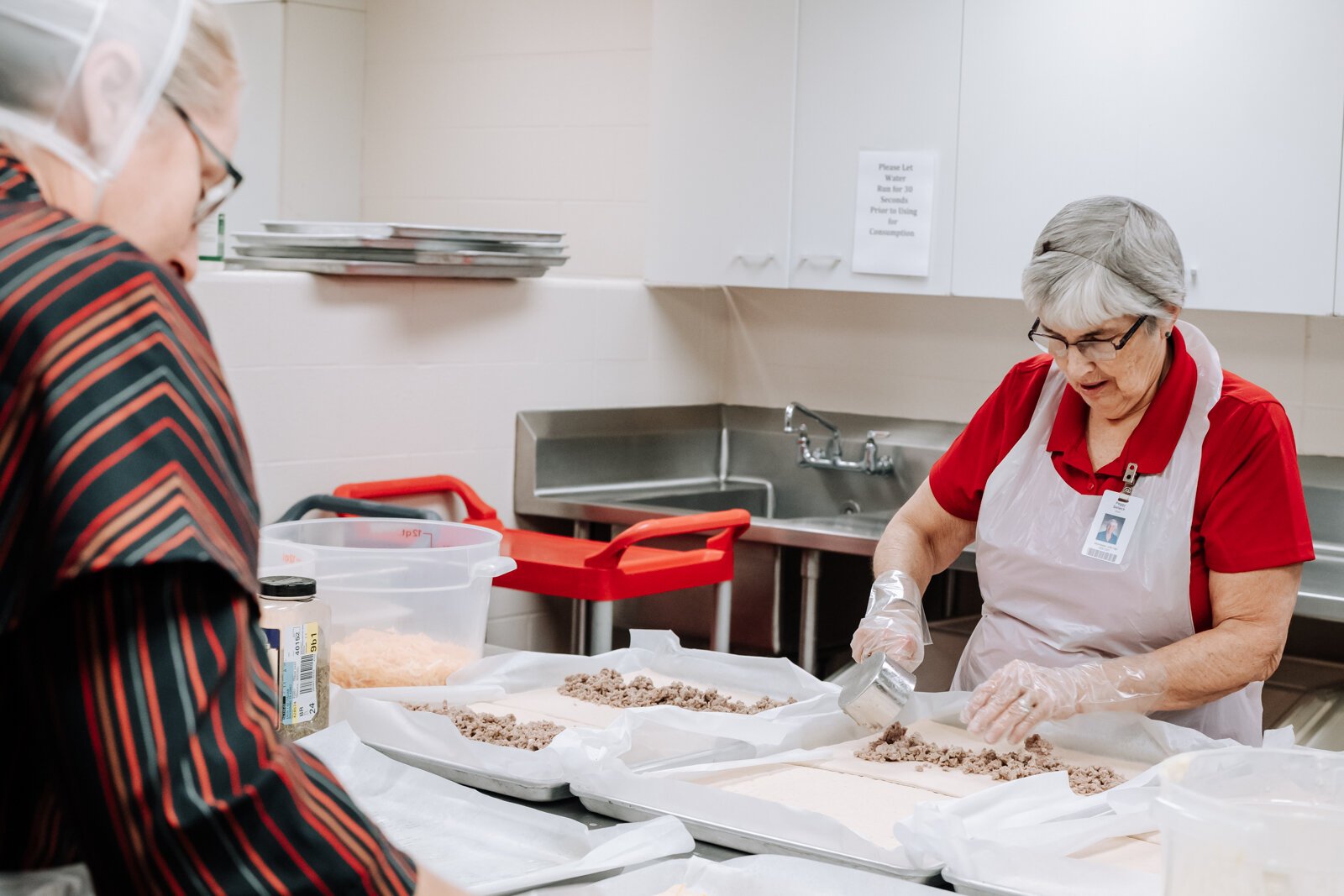 Landes's staff Judith Brovont, left, and Peggy Selleck prepare sausage bread for lunch at Manchester Junior-Senior High School with local pork from 4-H.