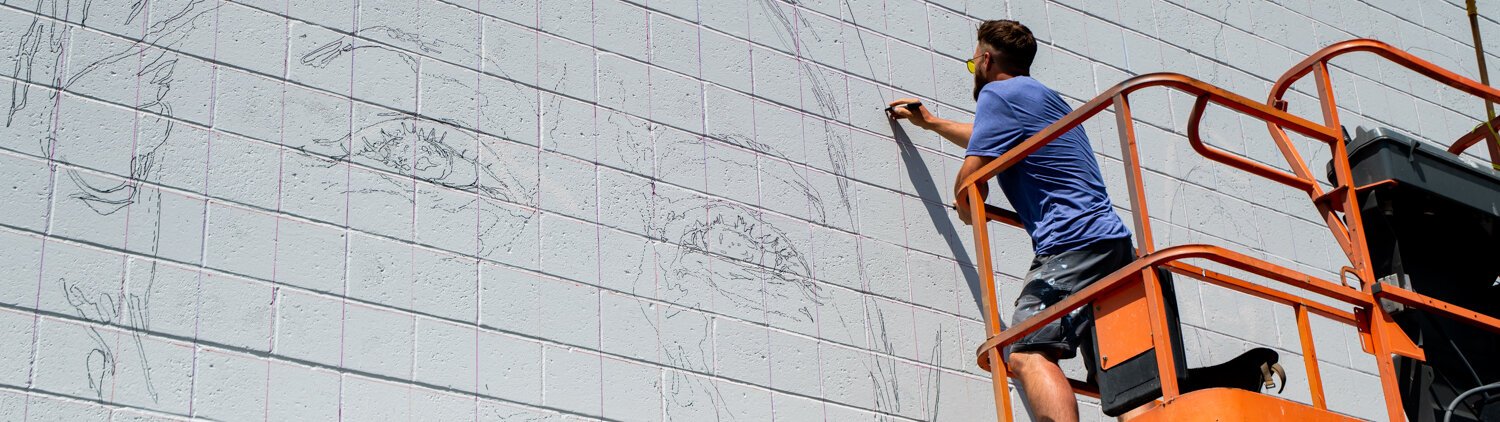 Muralist Mitchell Egly works on the Southwest Faces of the Fort mural at 1818 Bluffton Rd.