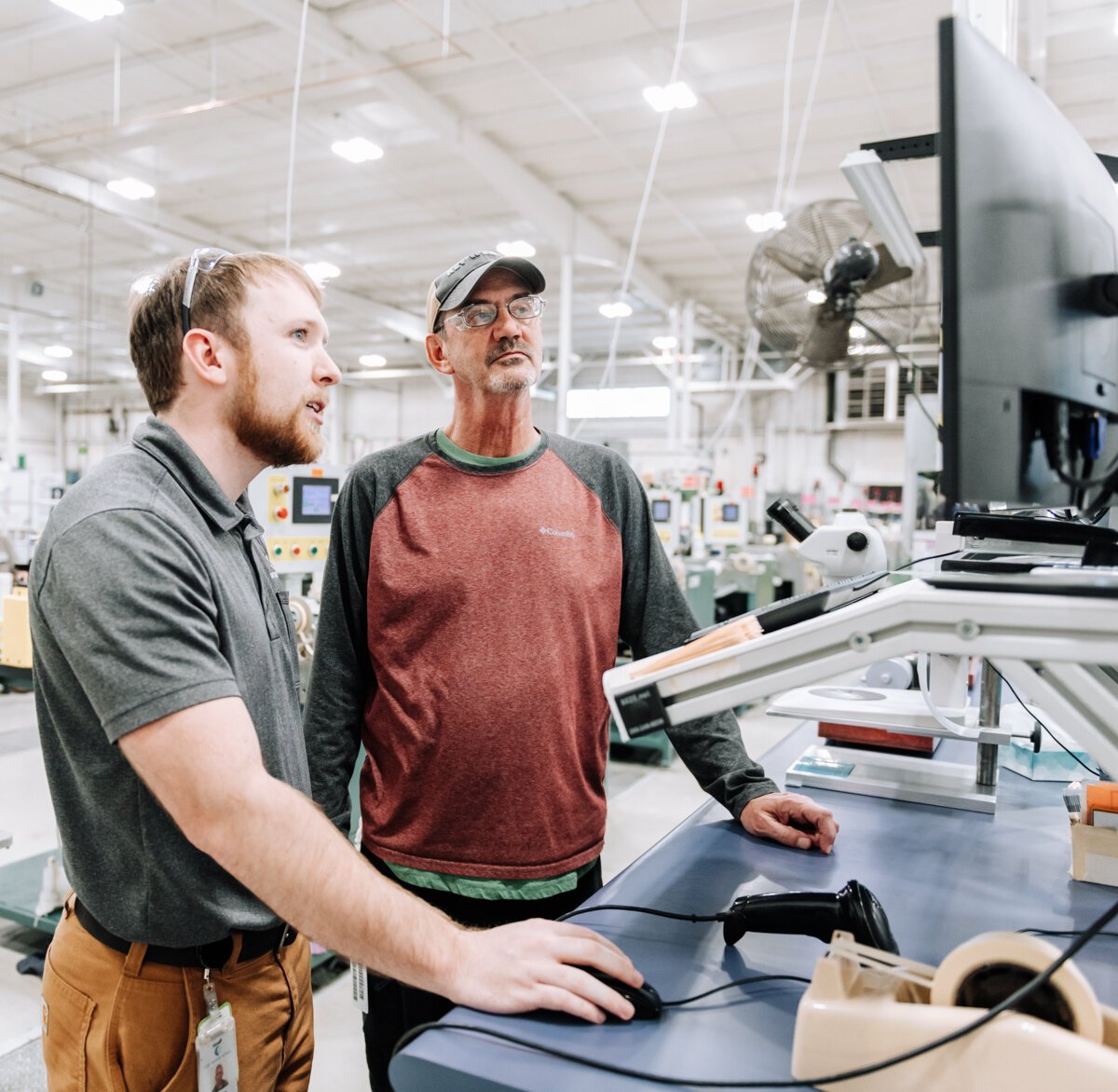 Blake Nicol, left, Senior Process Engineer works with Brad Peffley, Wire Drawer, using new technology that provides real time & historical data via a web interface that collects data from 70-80 machines in the one building in the Avionics Building.