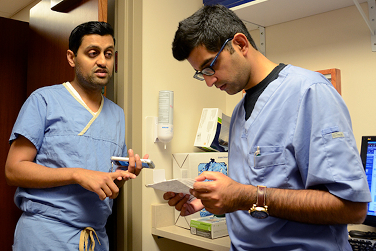 Gupta, right, takes notes from Sharma's instruction.