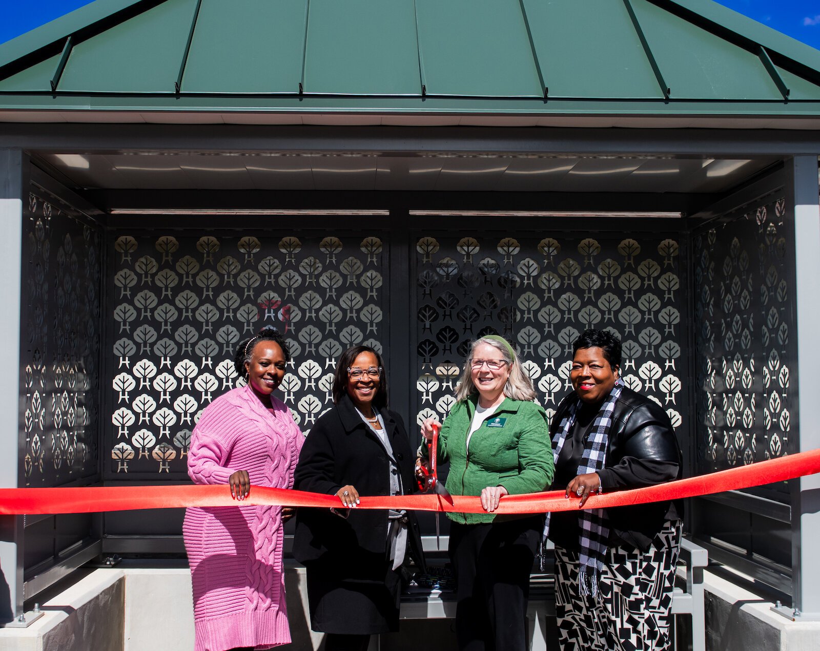 (From left) Councilwoman Rohli Booker, Mayor Sharon Tucker, Harvester Neighborhood Association President Margaret Machlan, and SE Area Partnership President Denita Washington pose at the bus shelter ribbon cutting ceremony.