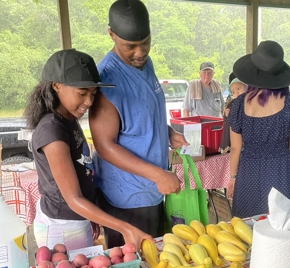 Shoppers explore the local produce offerings at the HEAL Market at HEAL MARKET Double up McCormick Place Apartments.