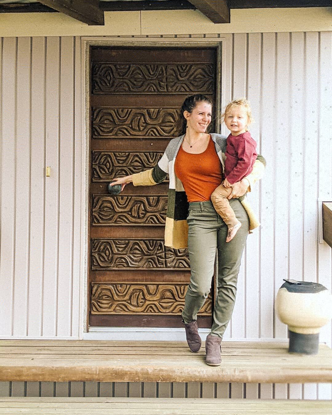 Alysha and her daughter stand outside the home's impressive wood-carved front door.