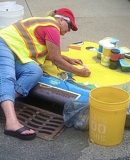 Joan Means paints a new mural on the corner of Calhoun Street and E. Masterson Avenue during Open Streets Fort Wayne.