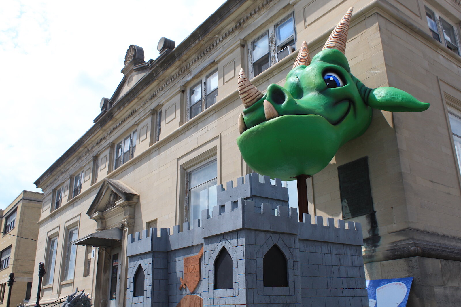 Charlie, the gigantic green dragon, welcomes customers to TCB Games.
