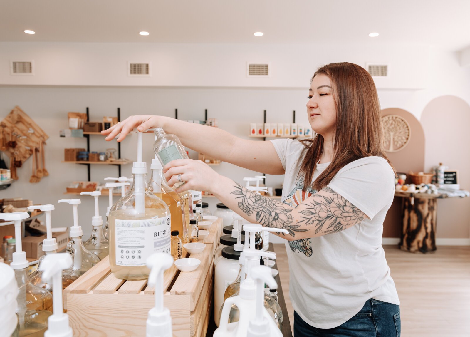 Bottle Green Refillery Owner Corinna Shoemaker refills a bottle with a lavender & lime essential oils bubble bath.