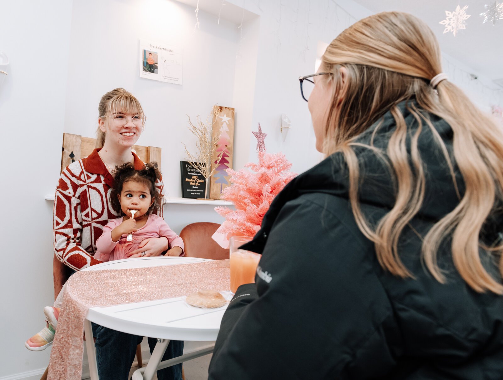 Cafe worker Lily "Cake Pop Lily" Bohde, left, sits with her sister Grace Bohde and Grayce's daughter Mia, 1.5, at Icing for Izaac.