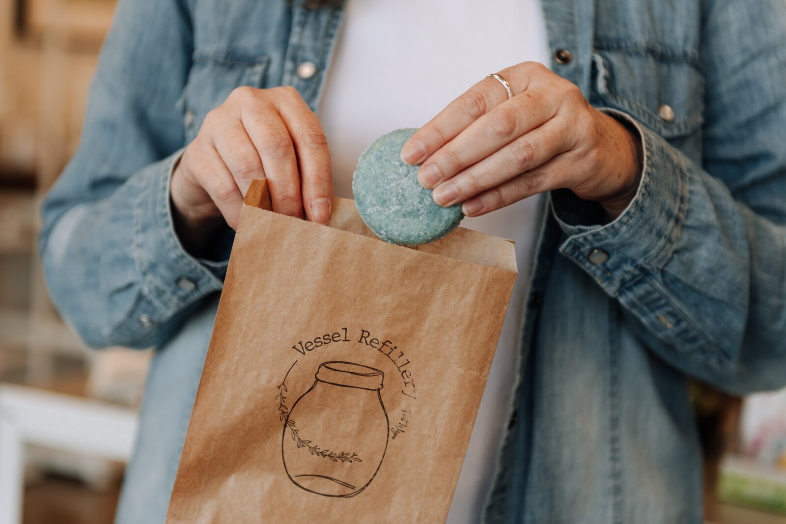 Heather Eracleous, owner of Vessel Refillery FW, puts a lemongrass, lime + rosemary shampoo bar in a bag.