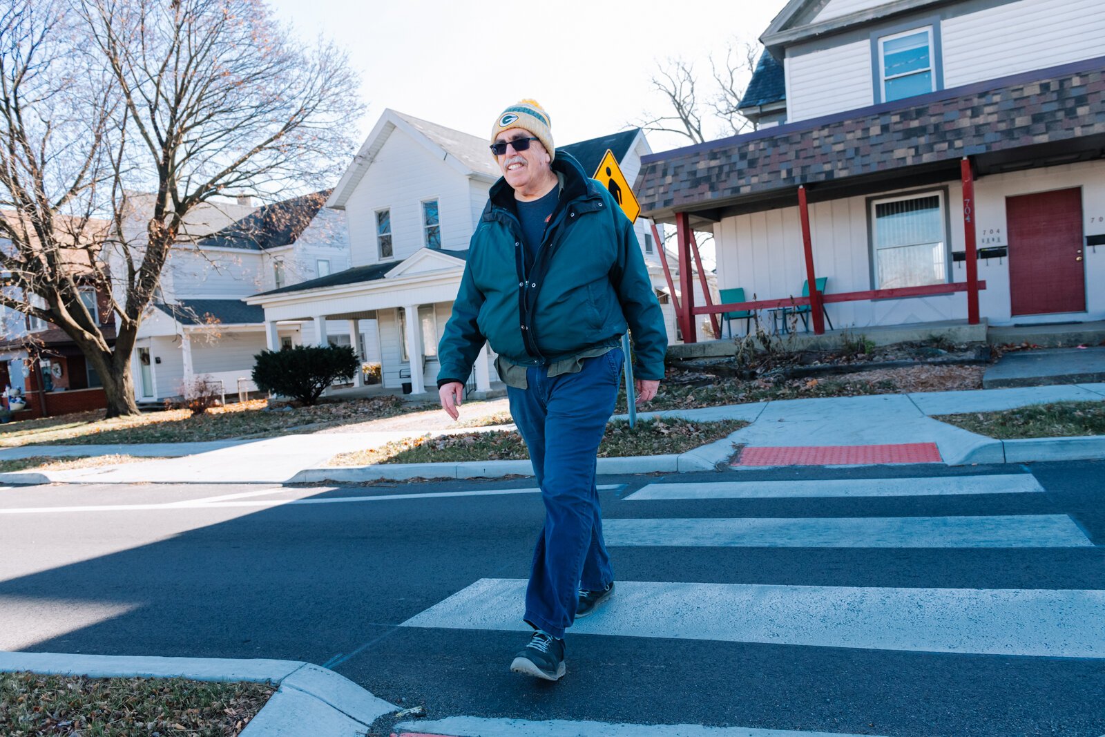 Mike Roeger crosses the street at a crosswalk on Columbia Avenue near Conjure Coffee in Fort Wayne.