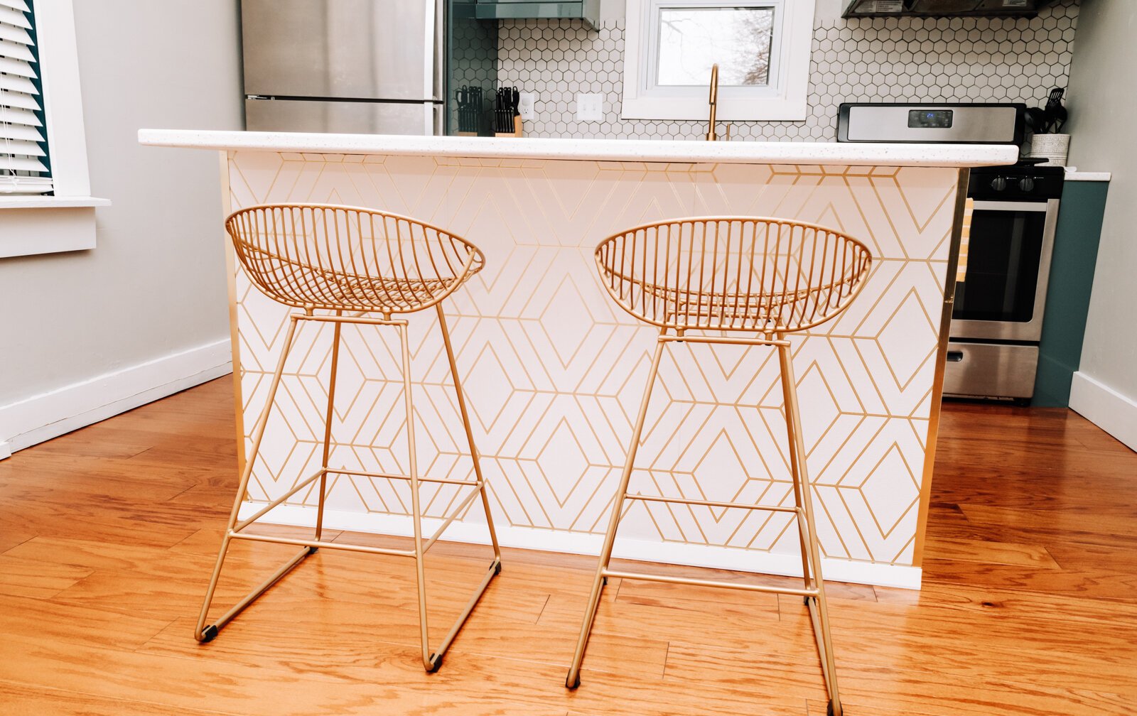 The addition of wallpaper on the island creates a pattern backdrop to the stools.