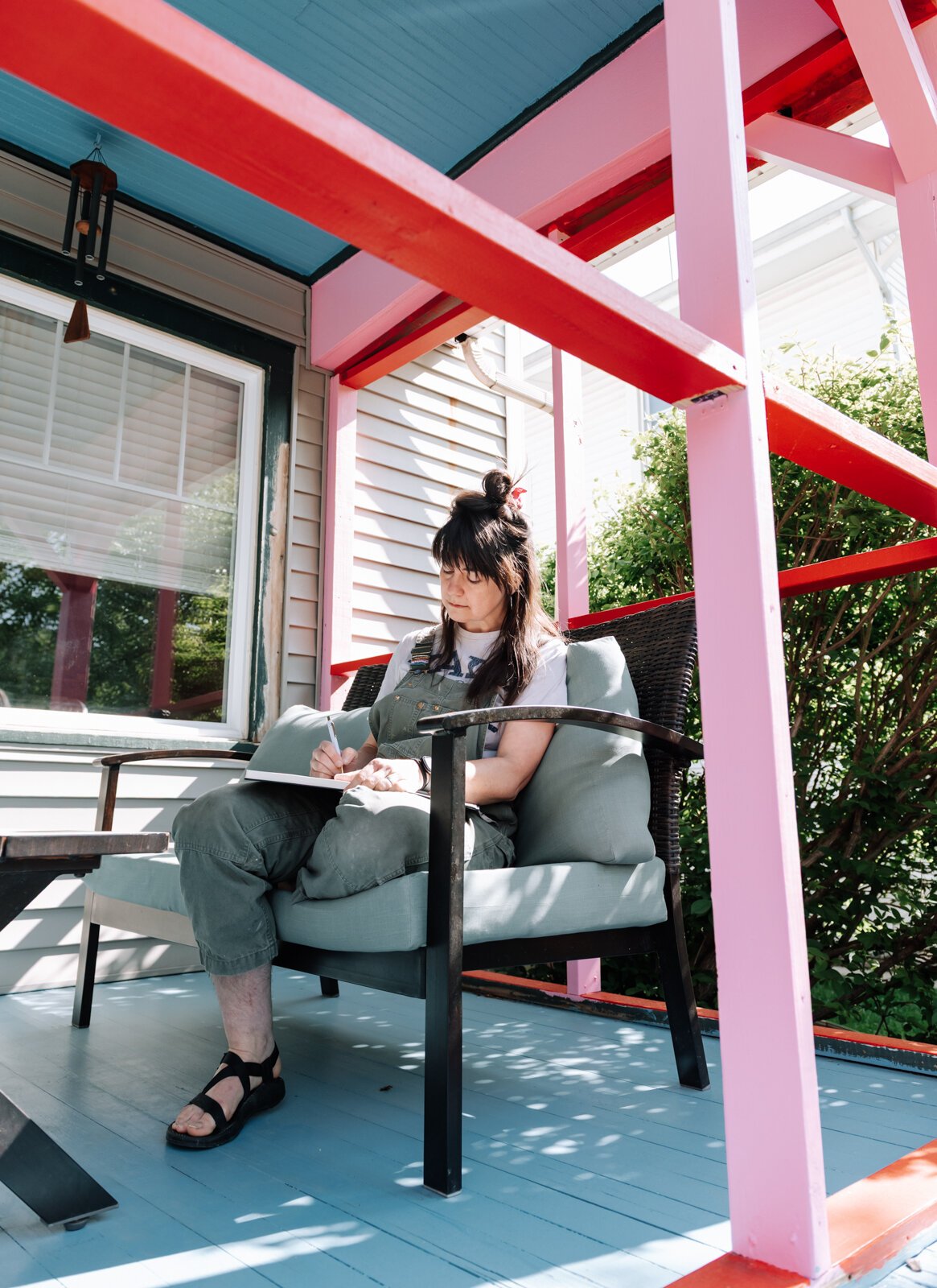 Sarah Wolfe, artist in residence, journals on the front porch while at 930 Illsley Drive.