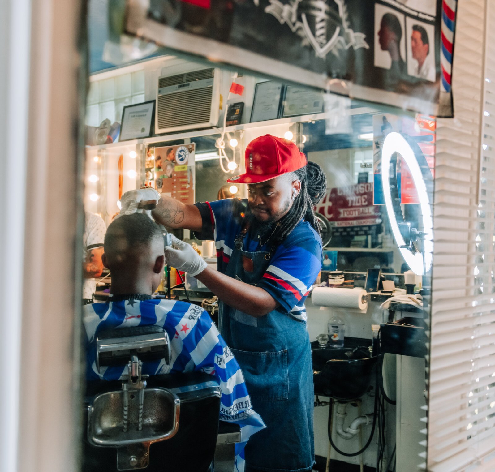 Barber Benson Harvey, owner of Smooth Kutz, works on giving Roderick Williams a bald fade.