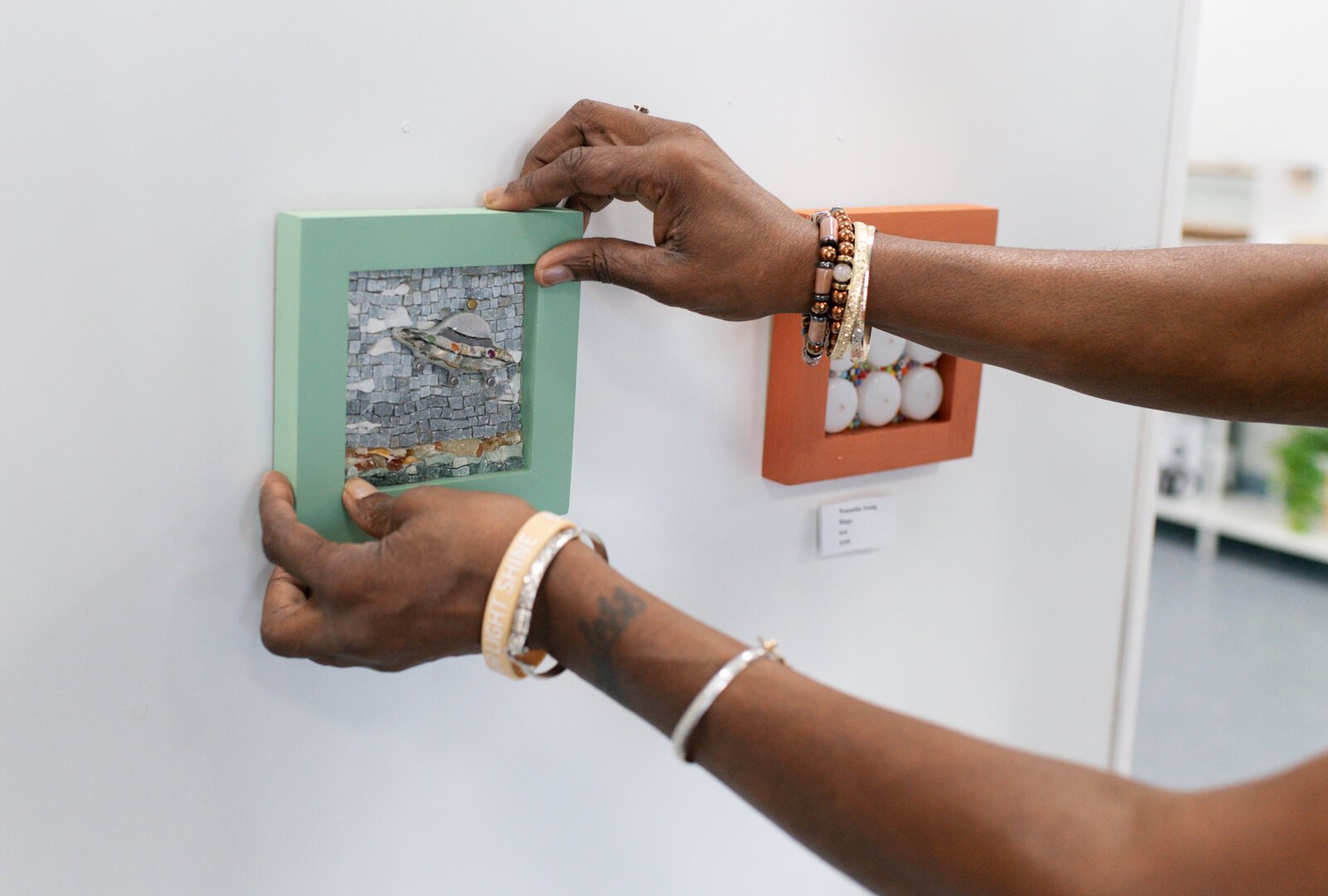 Clydia Early, owner of the BIPOCA Incubator and Gallery, works on hanging a piece from Wasentha Young.