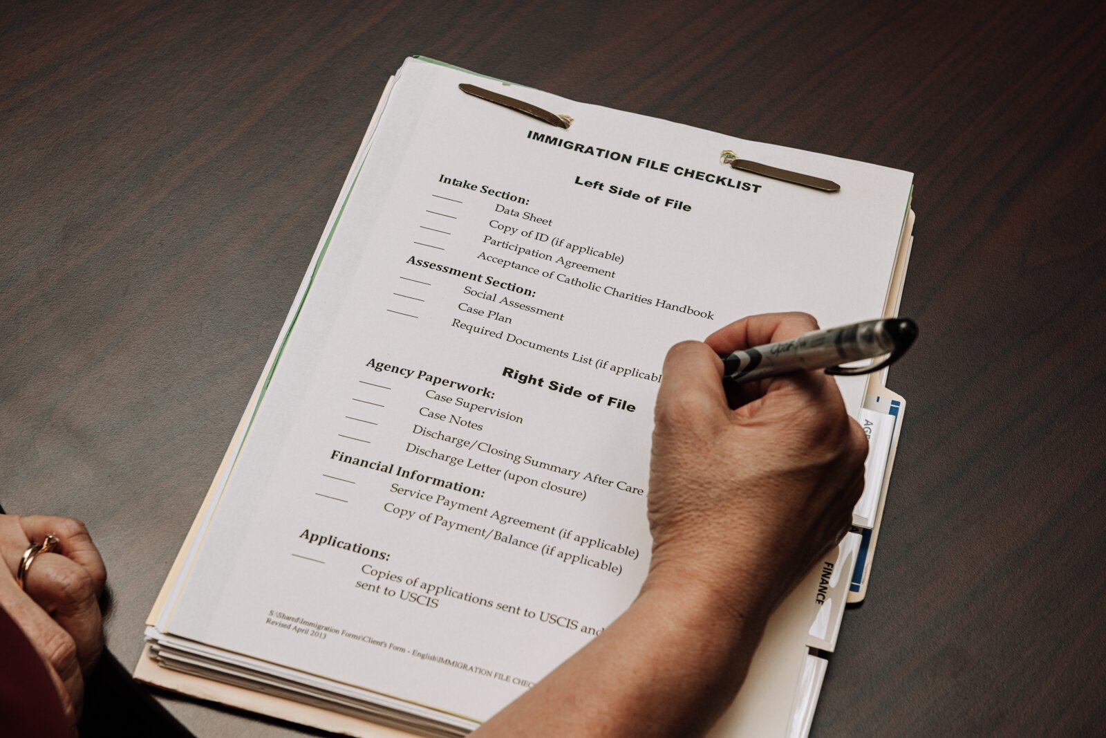 Luz Ostrognai with Catholic Charities fills out forms during a meeting.