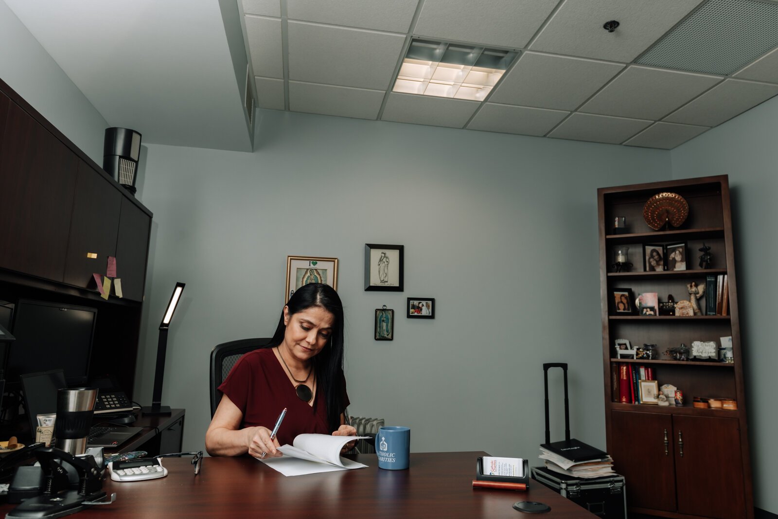 Luz Ostrognai with Catholic Charities works in her office at the Archbishop Noll Catholic Center.
