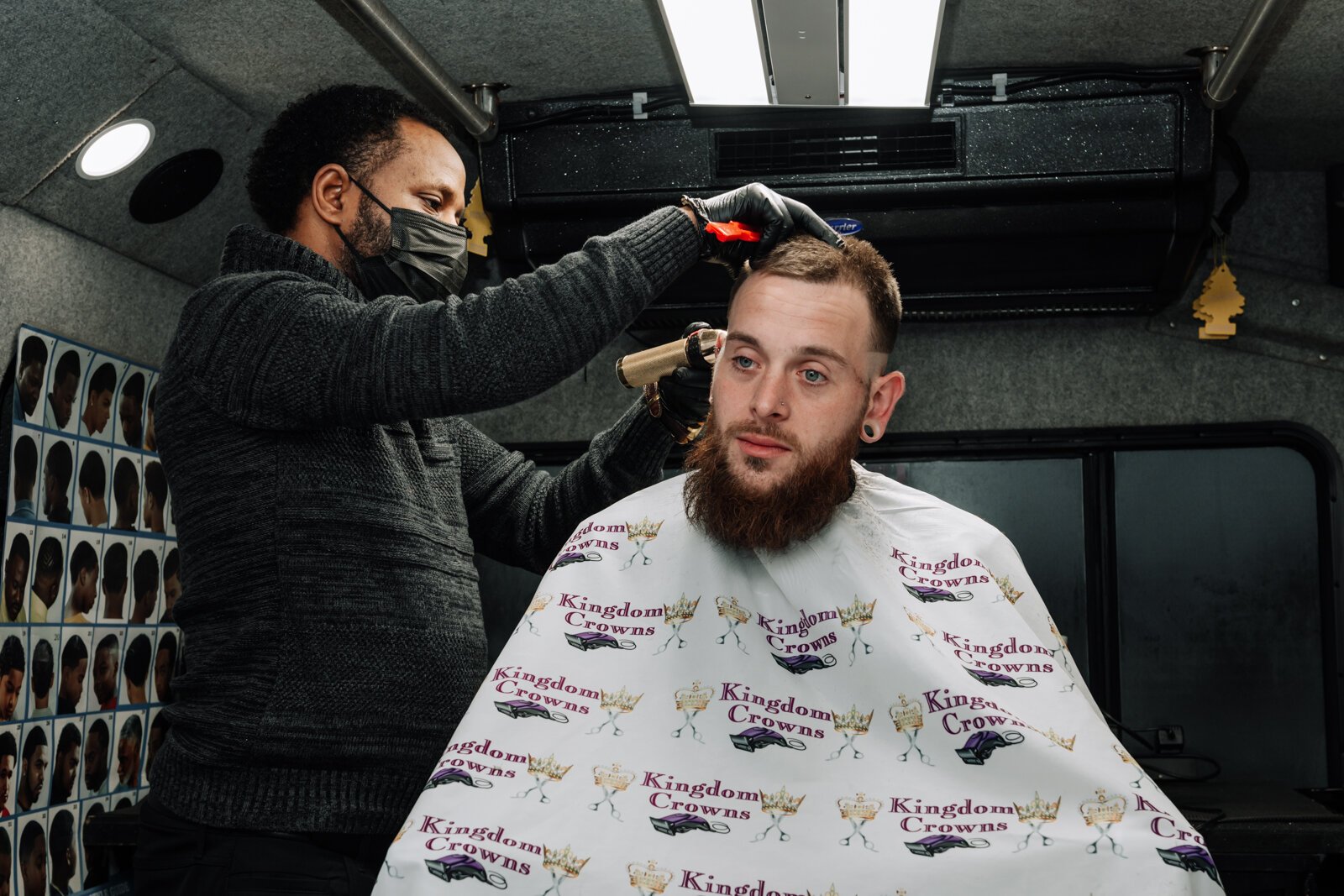 Elgien Richardson, owner of Kingdom Crowns Mobile Barbershop, works on giving client Larry Slater a bald fade & beard clean-up/line-up.
