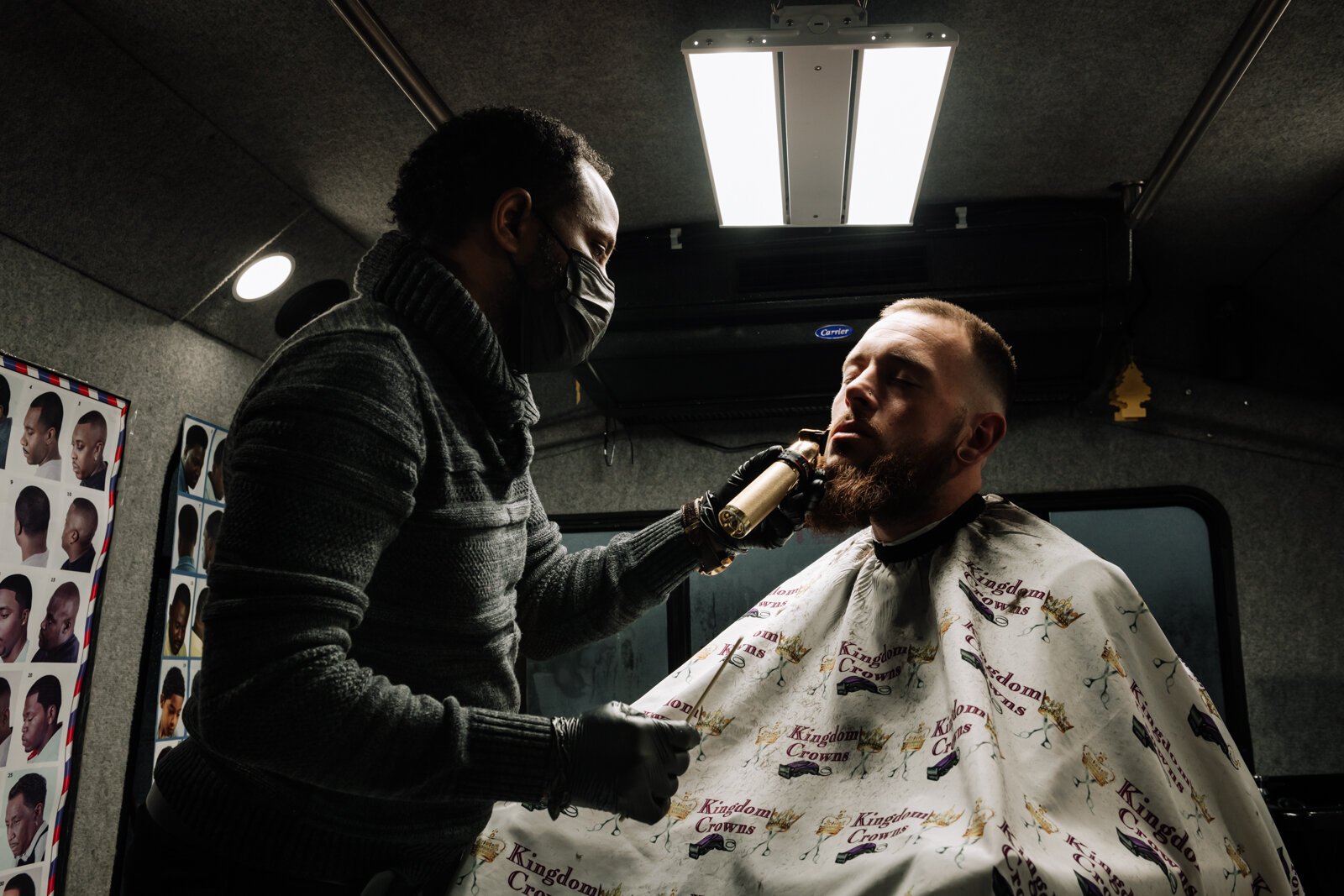 Elgien Richardson, owner of Kingdom Crowns Mobile Barbershop, works on giving client Larry Slater a bald fade & beard clean-up/line-up.