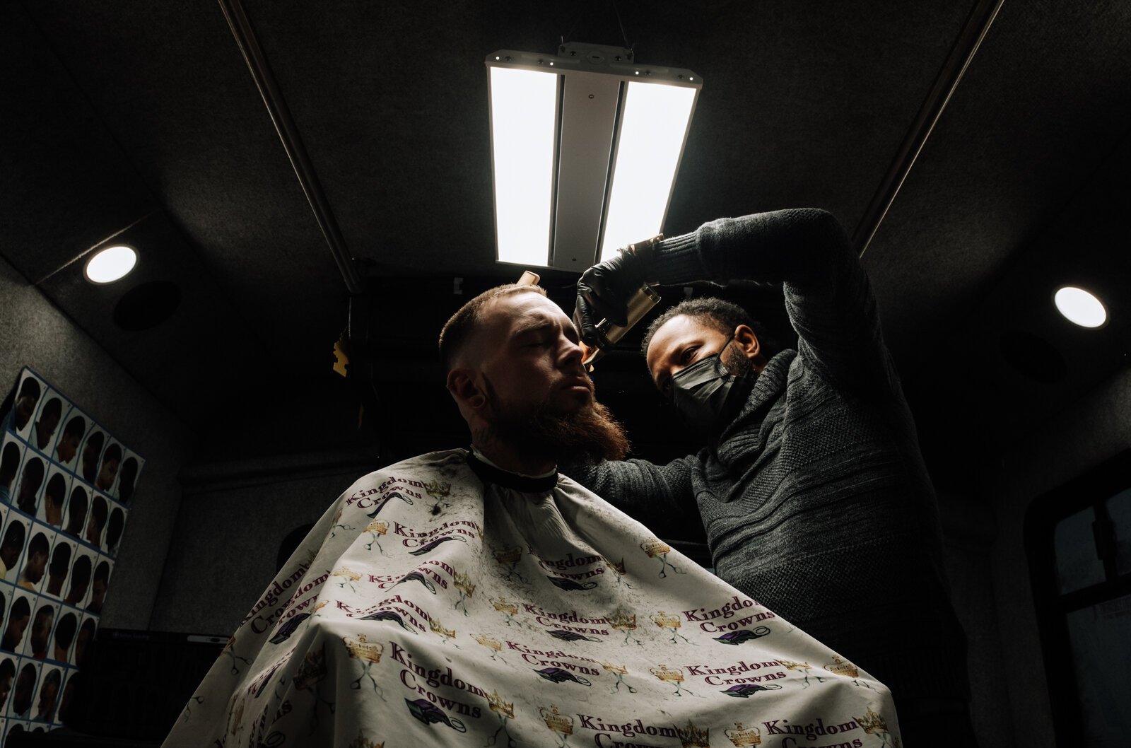 Elgien Richardson, owner of Kingdom Crowns Mobile Barbershop, works on giving client Larry Slater a bald fade & beard clean-up/line-up.