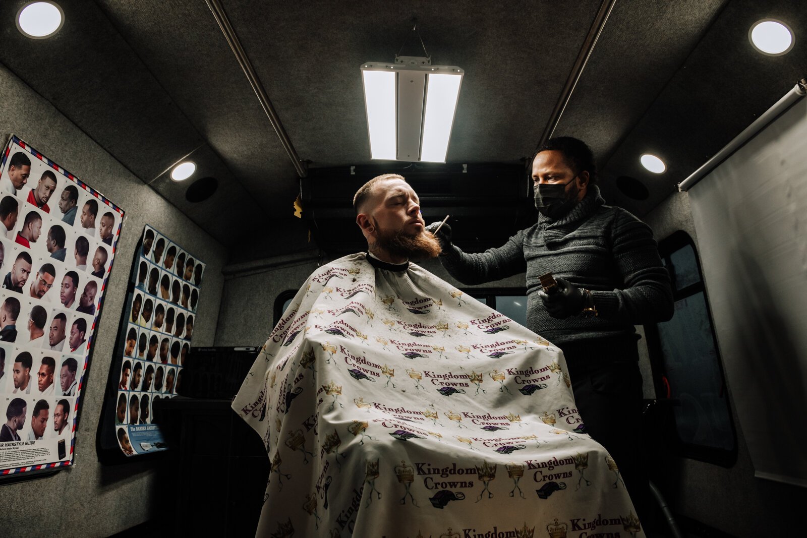 Elgien Richardson, owner of Kingdom Crowns Mobile Barbershop, works on giving client Larry Slater a bald fade & beard clean-up/line-up.