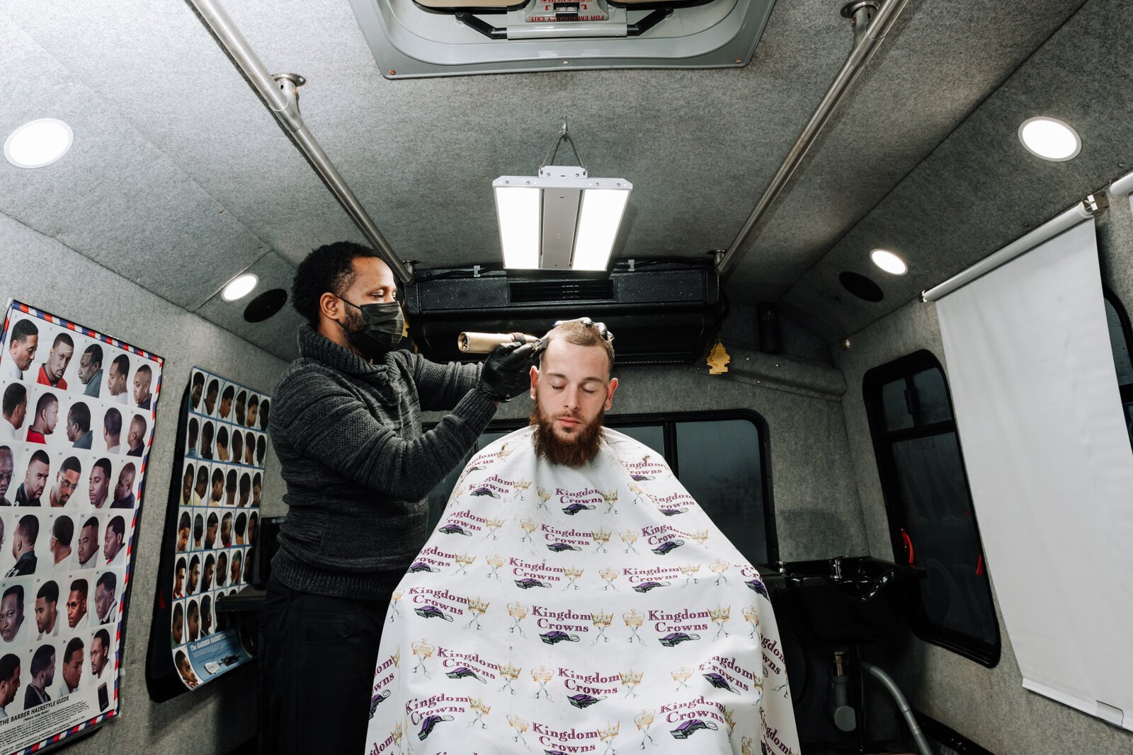 Elgien Richardson, owner of Kingdom Crowns Mobile Barbershop, works on giving client Larry Slater a bald fade & beard clean-up/line-up.