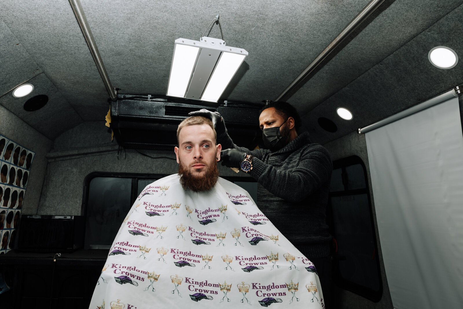 Elgien Richardson, owner of Kingdom Crowns Mobile Barbershop, works on giving client Larry Slater a bald fade & beard clean-up/line-up.