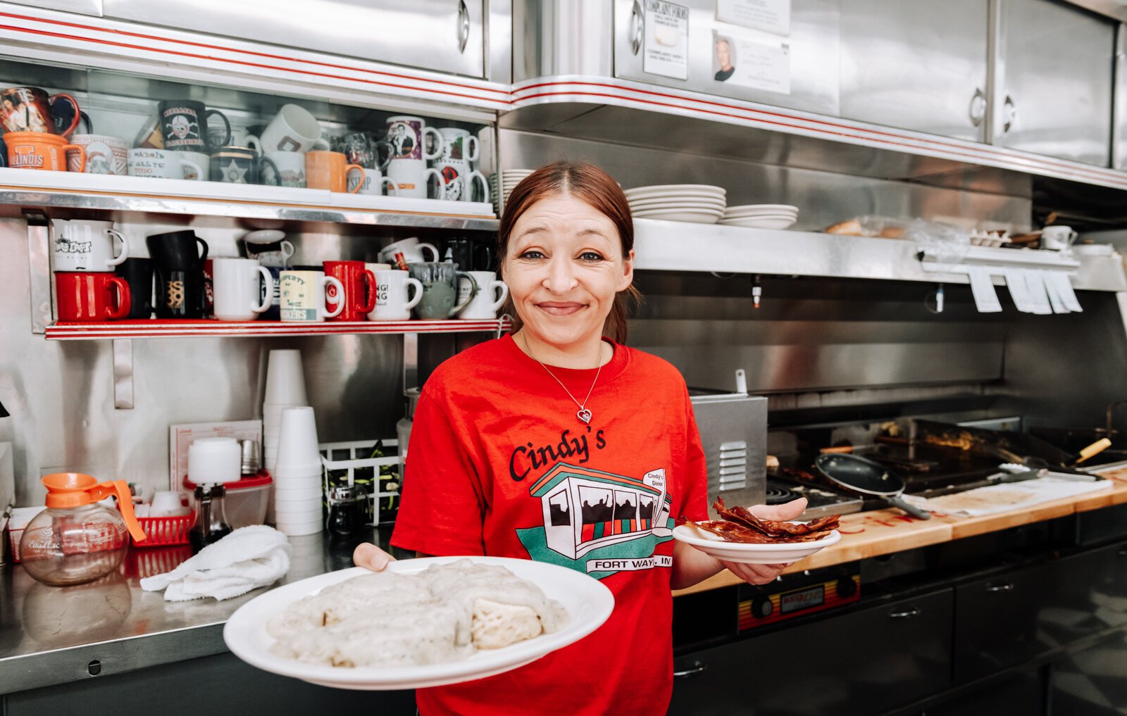 Server Sheila Williams serves a plate of country sausage gravy and biscuits with a side of bacon at Cindy's Diner, 230 W. Berry St.