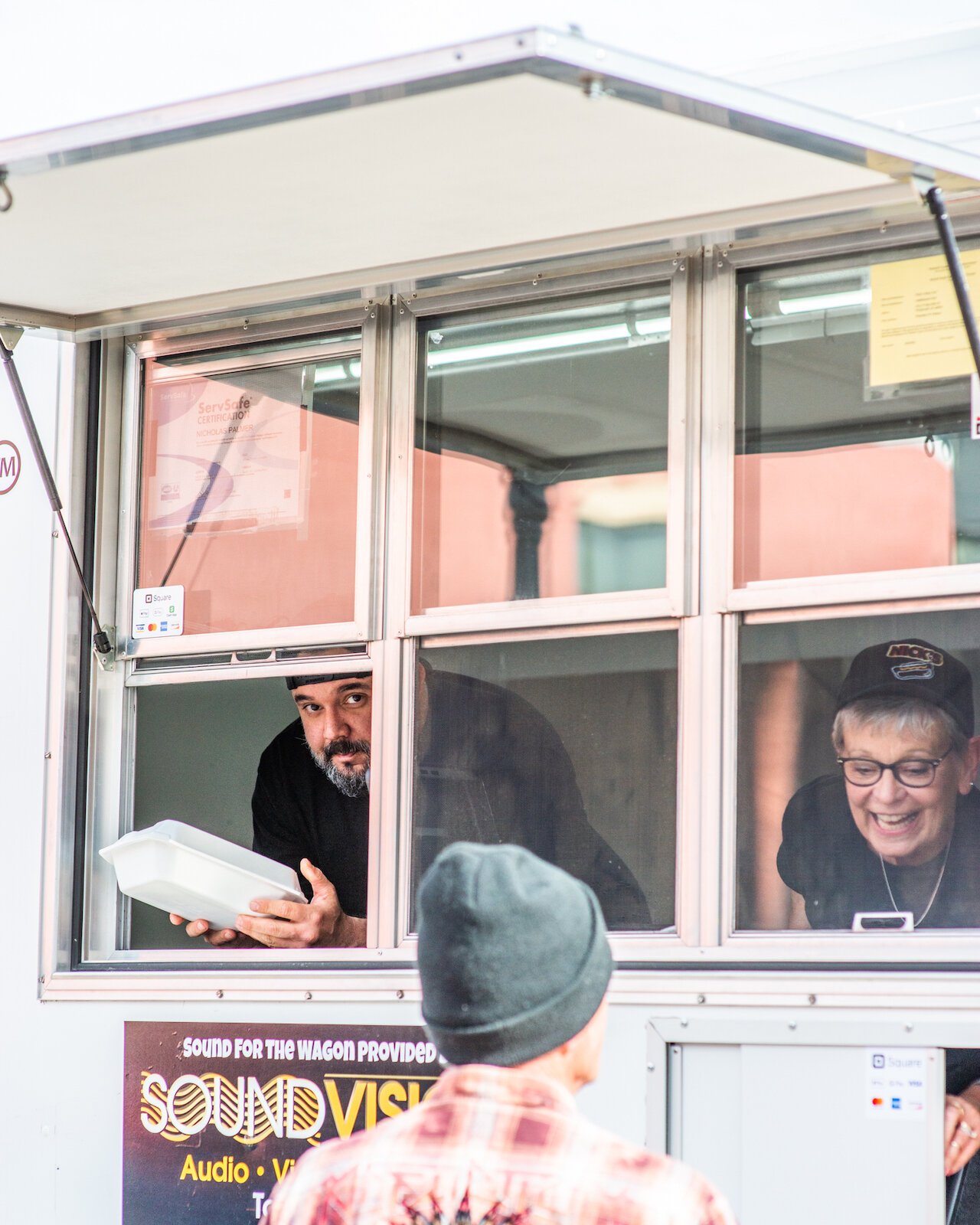 Nick Palmer, the owner of Nick's Dog Cart, hands a customer their food.