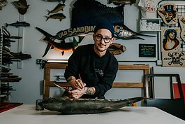 Sign painter Justin Lim, owner of Old 5 and Dime Sign Co., works on a vintage trout taxidermy at his shop in downtown Fort Wayne.