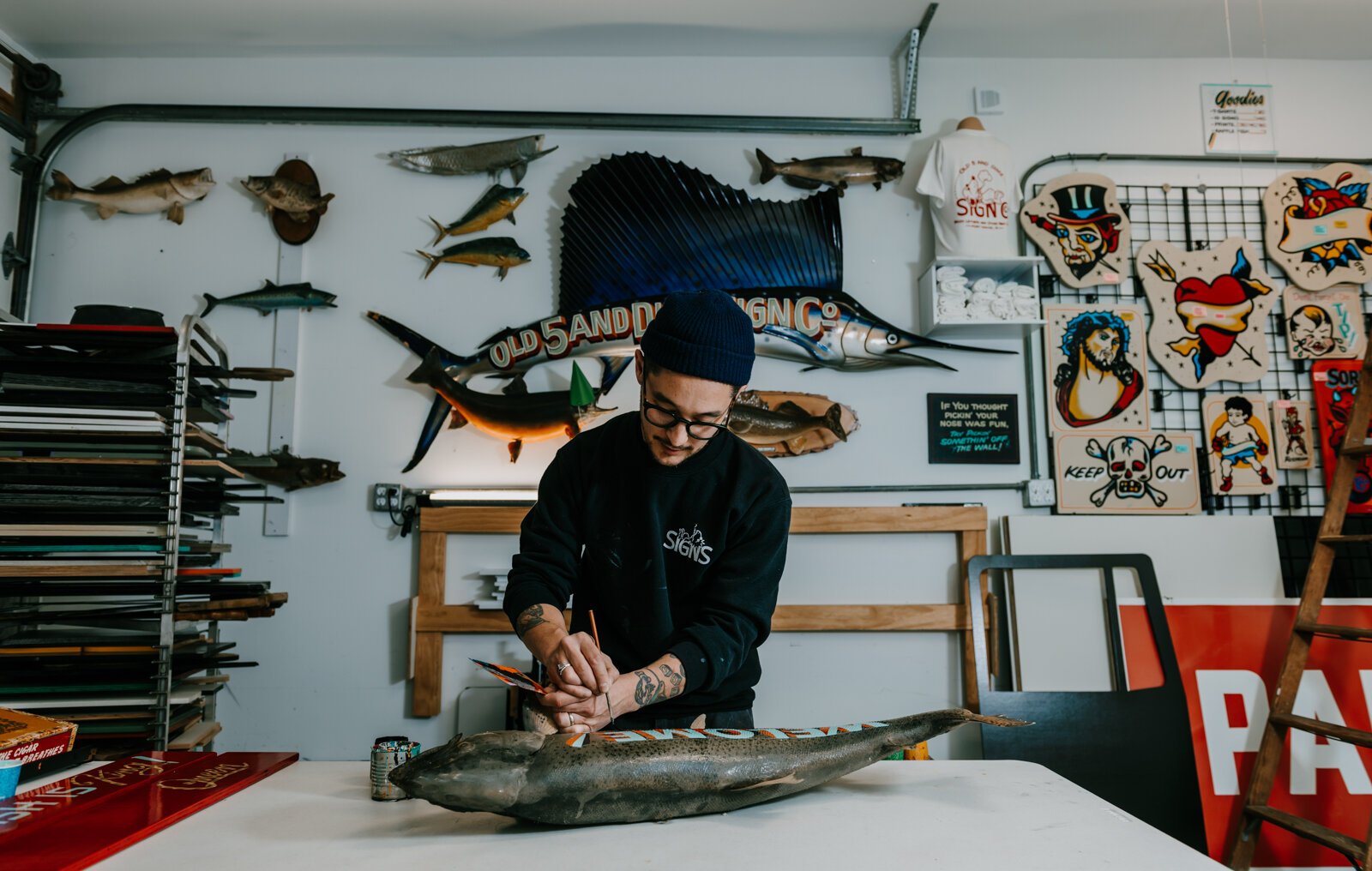 Sign painter Justin Lim, owner of Old 5 and Dime Sign Co., works on a vintage trout taxidermy at his shop in downtown Fort Wayne.