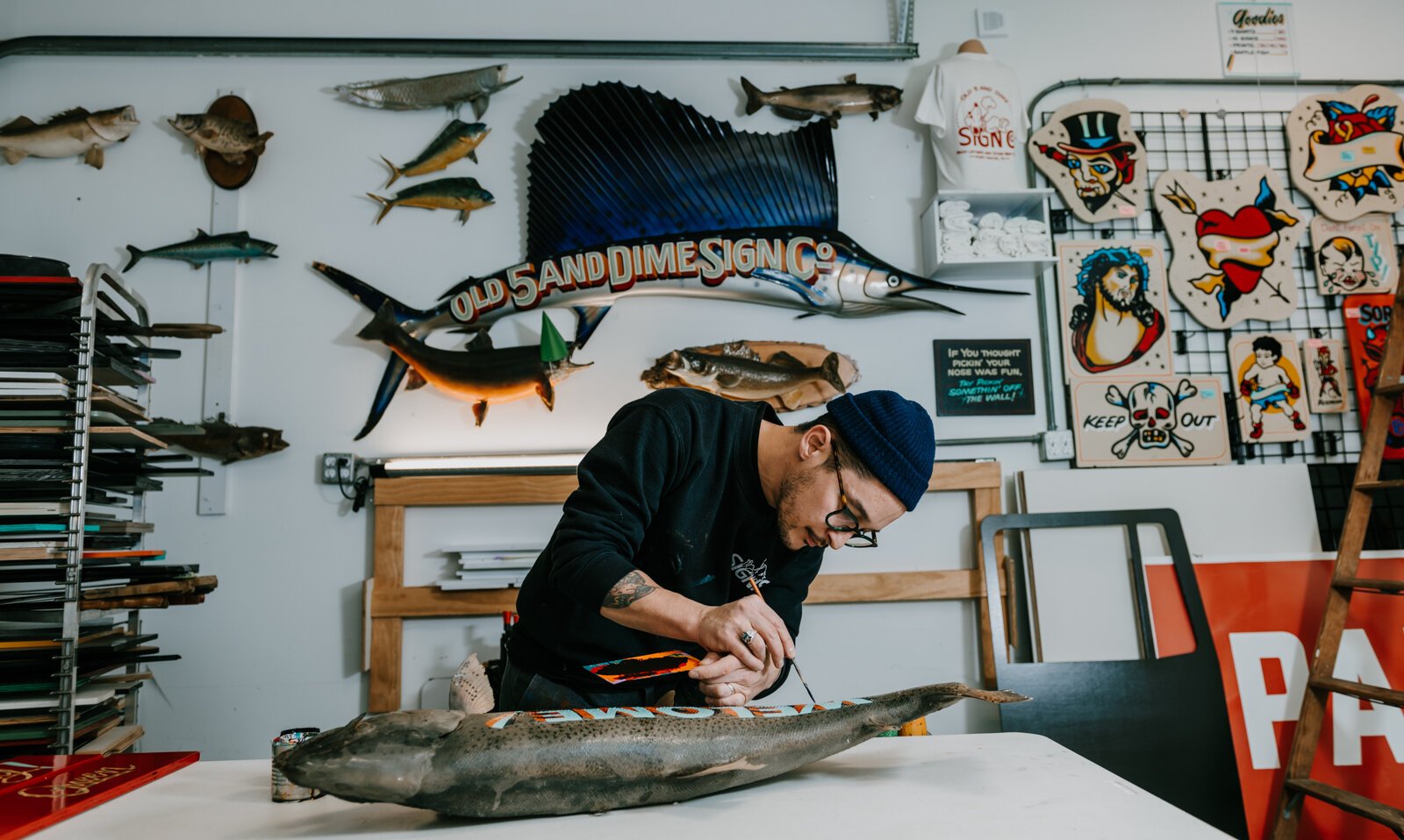 Sign painter Justin Lim, owner of Old 5 and Dime Sign Co., works on a vintage trout taxidermy at his shop in downtown Fort Wayne.