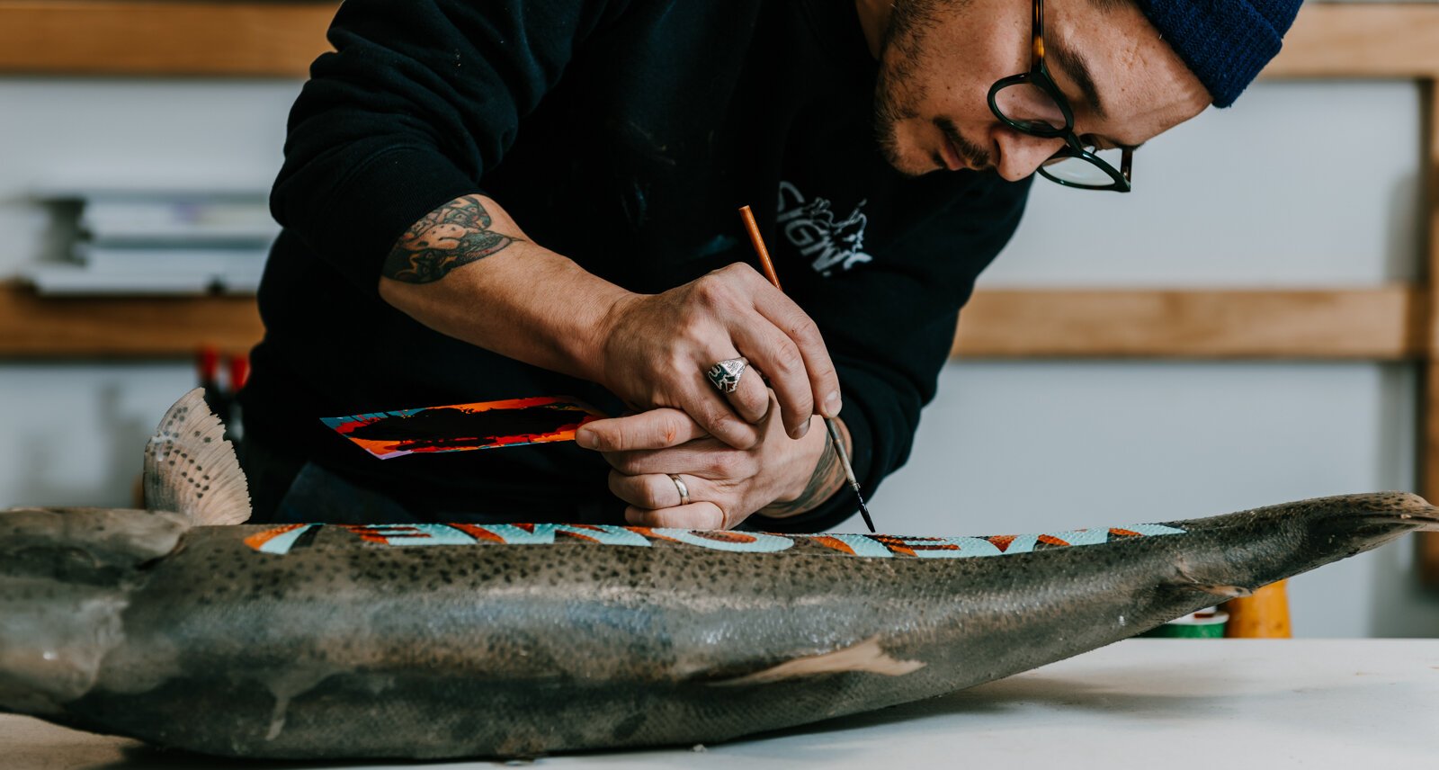 Sign painter Justin Lim, owner of Old 5 and Dime Sign Co., works on a vintage trout taxidermy at his shop in downtown Fort Wayne.