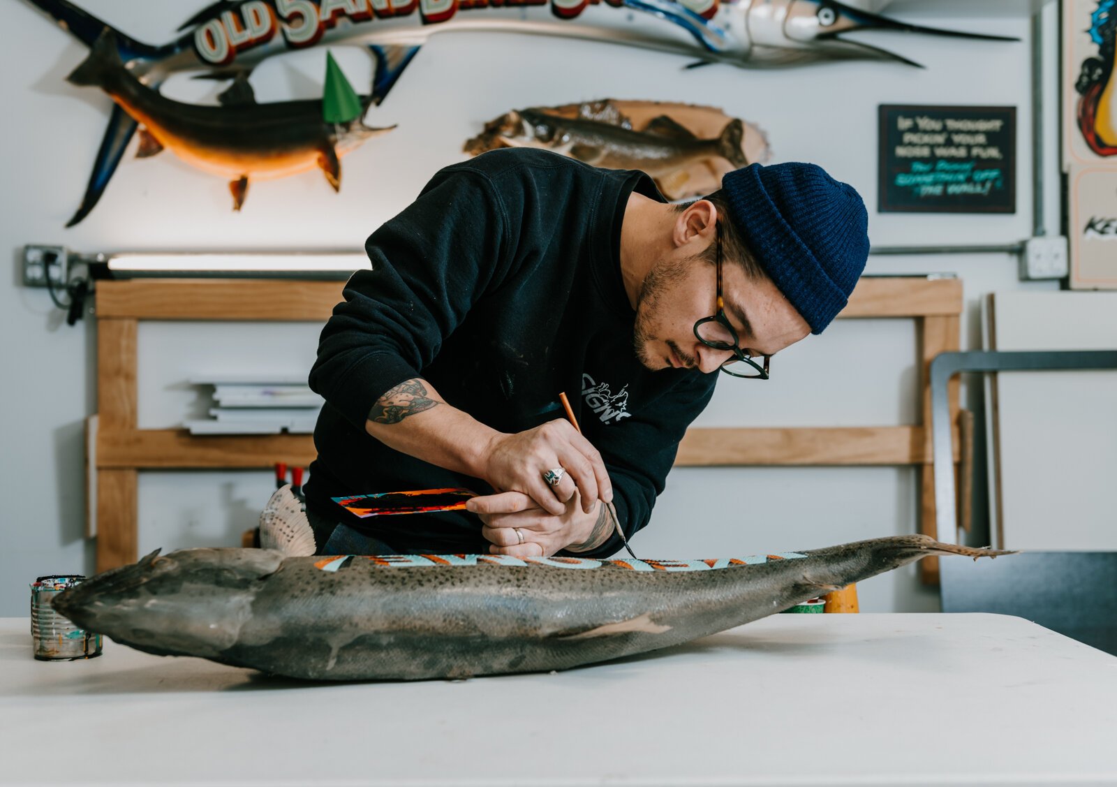 Sign painter Justin Lim, owner of Old 5 and Dime Sign Co., works on a vintage trout taxidermy at his shop in downtown Fort Wayne.